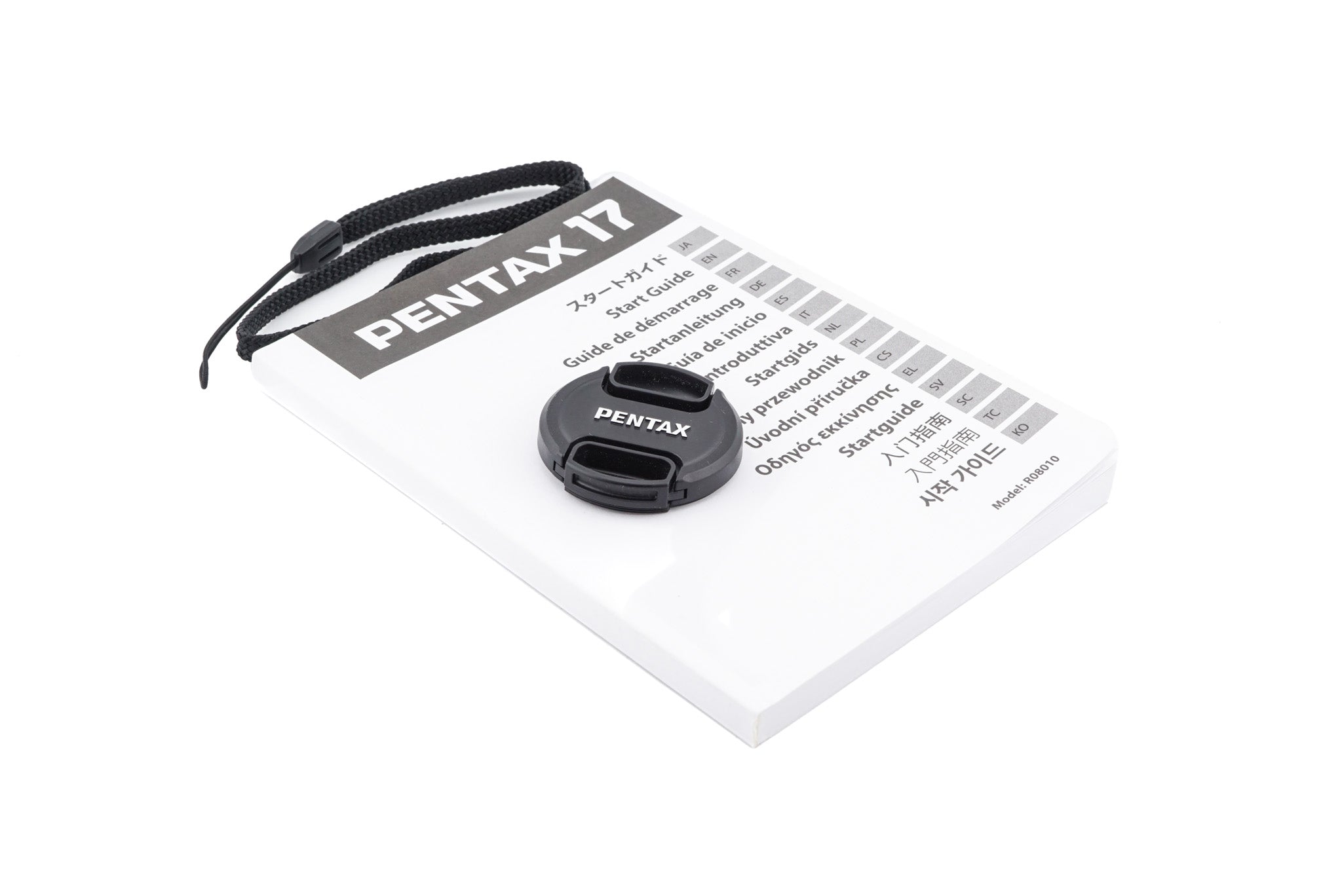 Pentax 17 half-frame camera lens cap and strap with a manual on a white background.