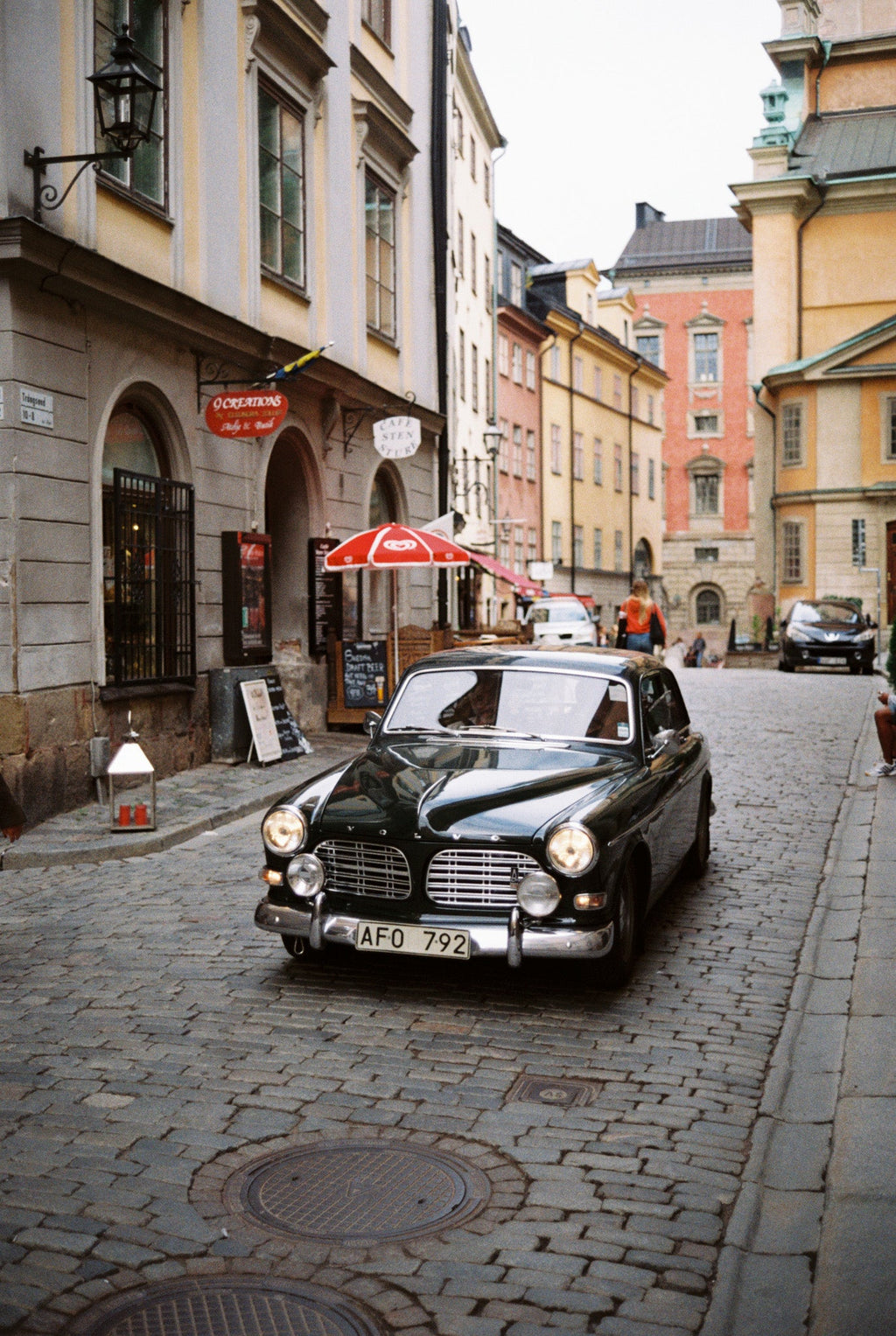 An old automobile in the middle of a city street.